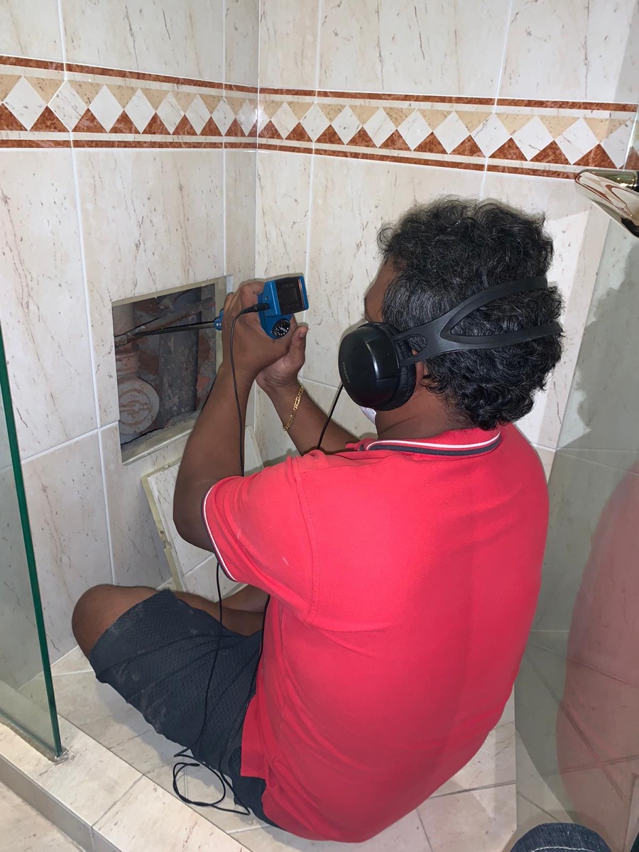 Licensed technician using acoustic leak-detection equipment on a residential job